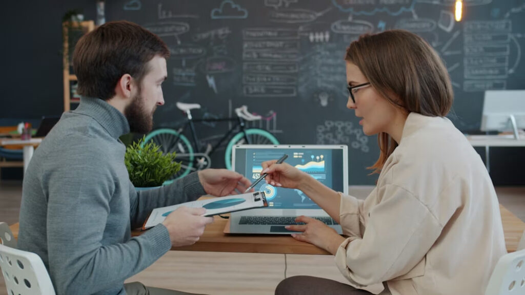 2 personnes parlent dans un bureau devant un ordinateur