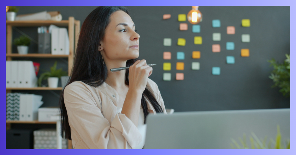 Une femme qui réfléchit avec un stylo sur son bureau