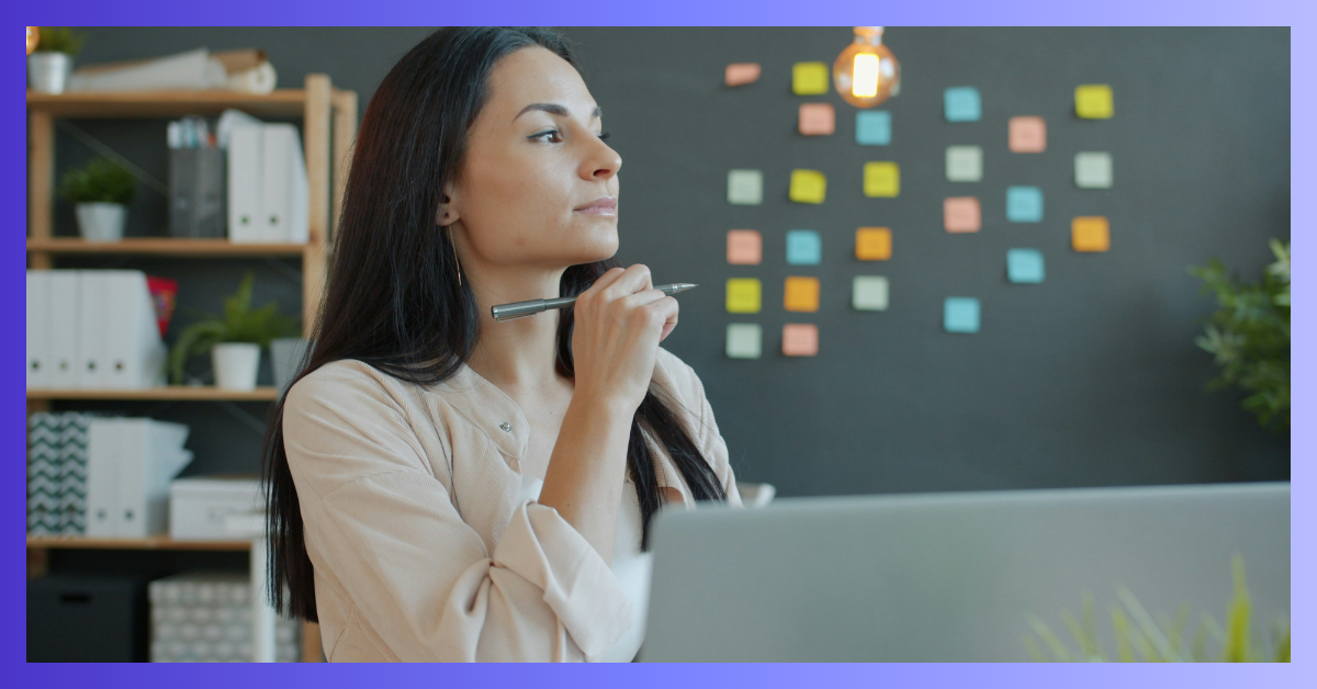 Une femme qui réfléchit avec un stylo sur son bureau
